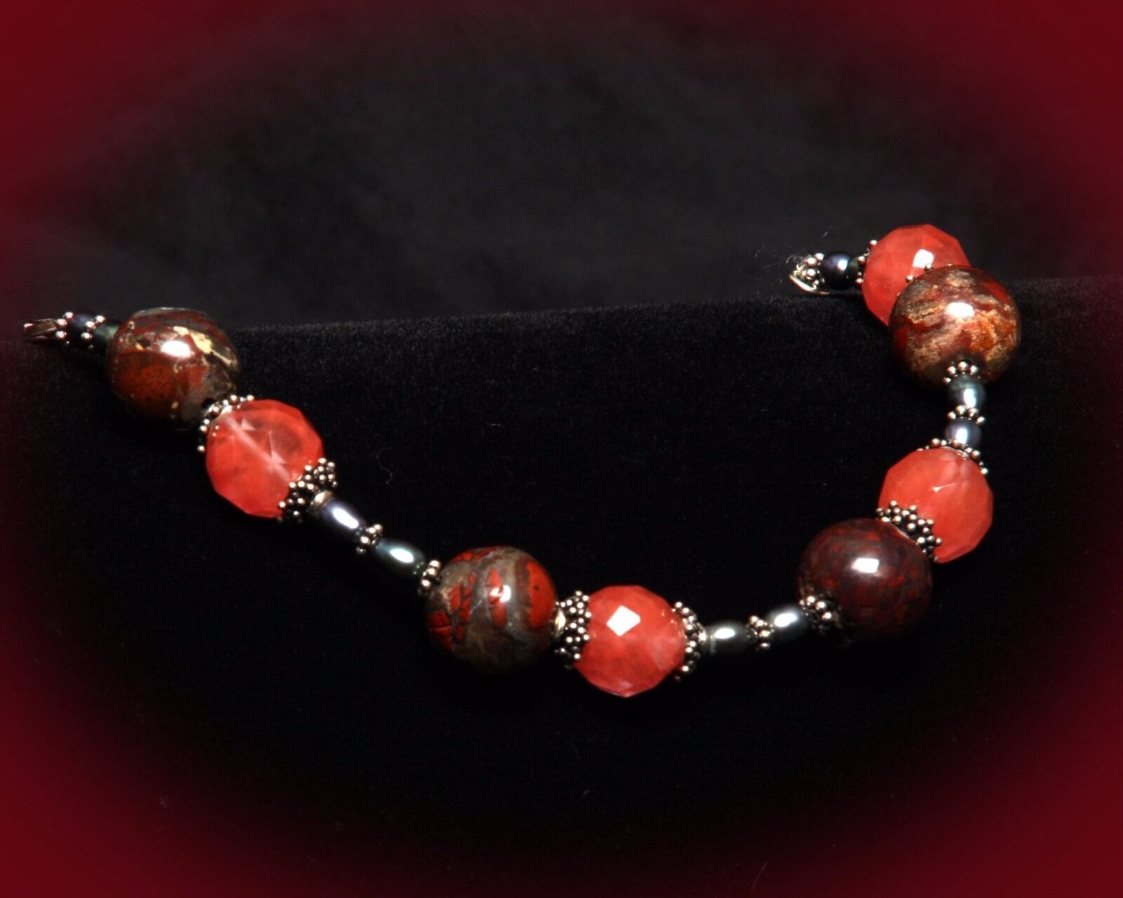 A red and brown bracelet is shown on a black background.