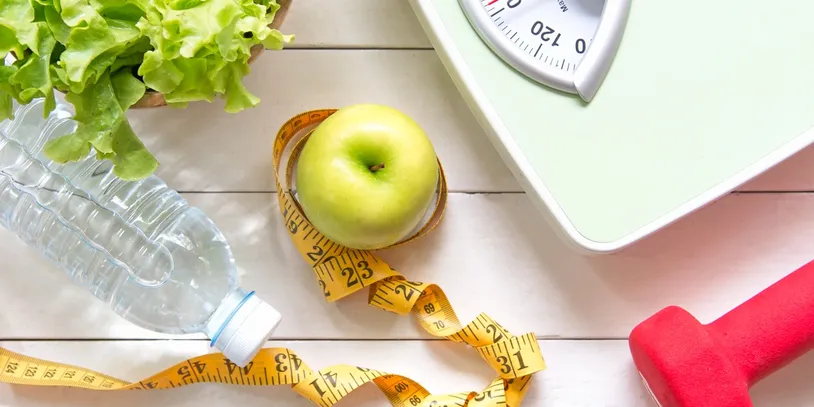 cr=w_814,h_407 Healthy lifestyle: apple, water, scale, weights.