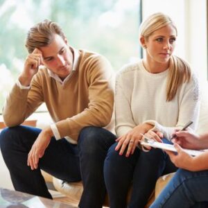 Here's an alt tag for the image: `Couple in therapy session, looking concerned.`