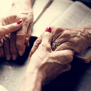 Elderly hands clasped in prayer.