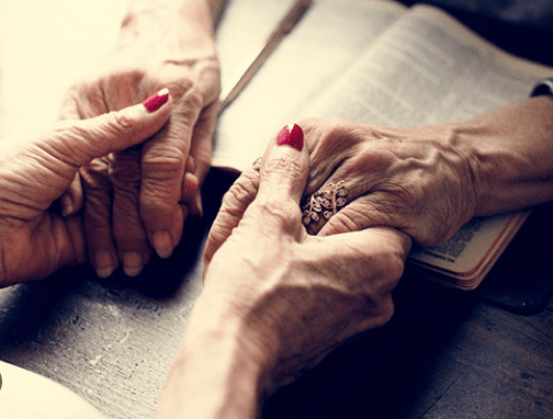 Elderly hands clasped in prayer.